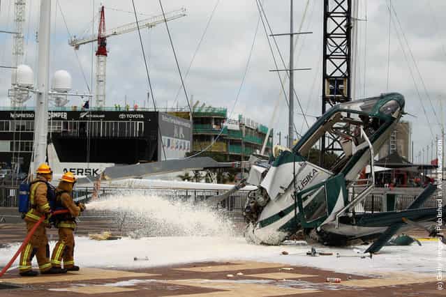 Firefighters spray foam at the scene where a helicopter crashed while installing a large Christmas Tree at the Viaduct Harbour on November 23, 2011 in Auckland, New Zealand