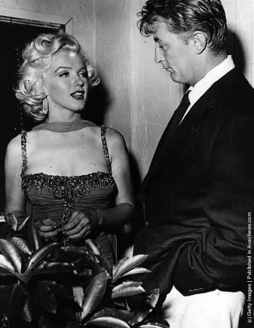 American actress Marilyn Monroe (1926 - 1962) with actor Robert Mitchum (1917 - 1997) at a Hollywood party