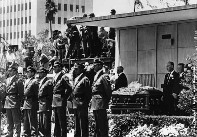 Detectives from the Pinkerton Agency in powder-blue uniforms with white silk scarves at their throats guard the coffin of American actress Marilyn Monroe, in Westwood Memorial Park, Hollywood, not far from the orphanage where she was brought up