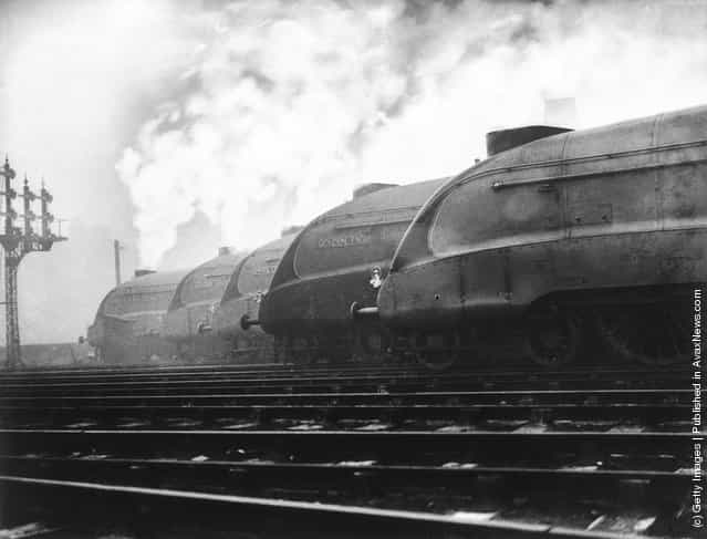 A row of LNER streamlined locomotives belch out smoke at a London railway station, where they are to be tested out