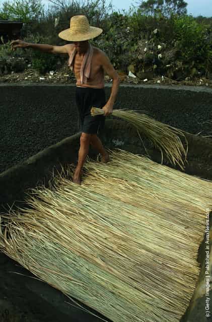 A villager prepares straw at ancient salt fields in Yantian Village on Hainan Island, China