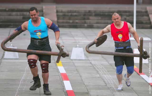 Carl Waitanen of New Zealand (L) and Gu Yanli of China carry anchors during a match of the 2005 Worlds Strongest Man Competition at Wuhou Temple