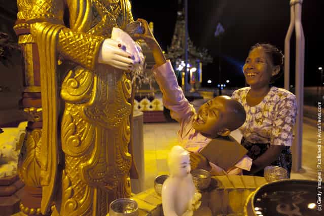A young Burmese nun gives a traditional blessing by pouring water on Buddha statue at the Ouparta Thandi pagoda
