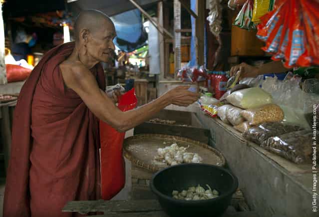 An elderly monk visits a market to collect donations of food and money