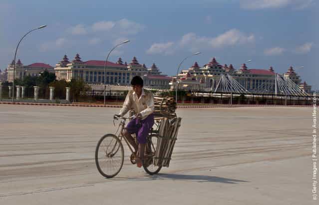 A Burmese man cycles past the massive parliament complex