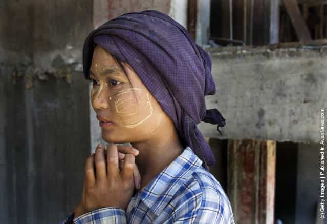 A Burmese woman, who is a construction worker, takes a break from carrying bags of cement