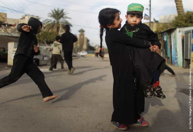Haneen Muaid holds her brother Aiad Muaid outside Seid Idrees mosque on the day before the festival Ashura