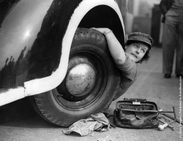 A member of the Mechanised Transport Training Corps changes a wheel at an ARP post in Lambeth, south London, 1939