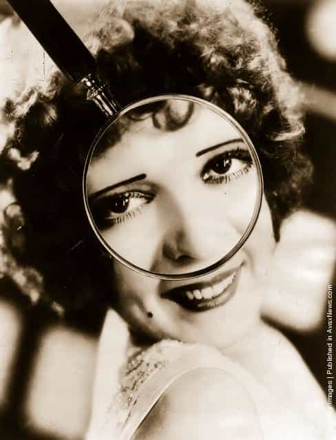 1927: Portrait of Clara Bow through a magnifying glass, captioned Is Clara Bows charm in the sparkle of her eyes?