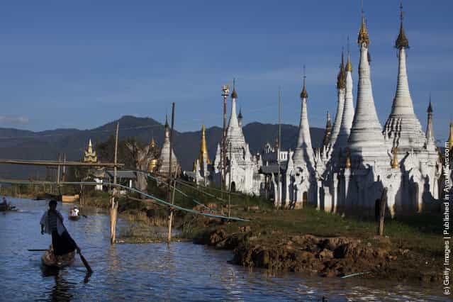 A man paddles his boat past a pagoda along Inle Lake December 16, 2011 in Inle Lake, Myanmar