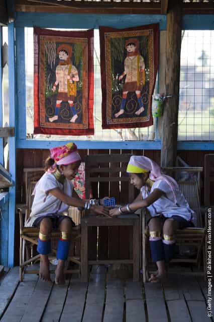 Burmese Long Neck children play as they wait for tourists to arrive at a handicraft shop on Inle Lake