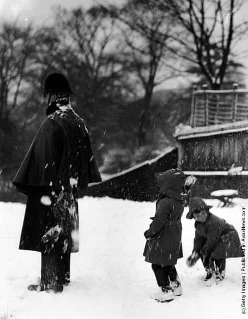1960: Two children throwing snowballs at a policeman
