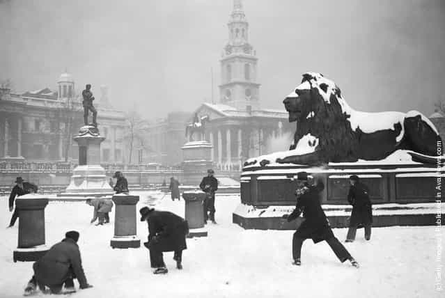 1931: A group of gents enjoy an impromptu snowball fight in the serene and stately setting of a still and snow covered Trafalgar Square, London