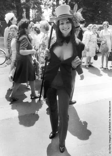 1974: Erotic actress Linda Lovelace (1949 - 2002) wears a top hat and tails with pinstripe trousers to the third day of Royal Ascot
