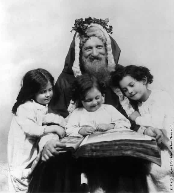 1915: Father Christmas reading with three young children