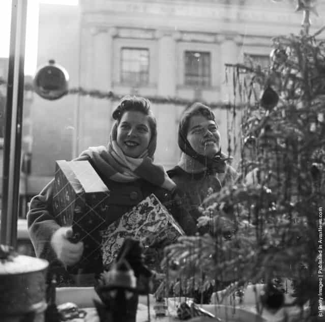 1955: Happy Christmas shoppers happily gaze at the window displays of the shops of Washington DC