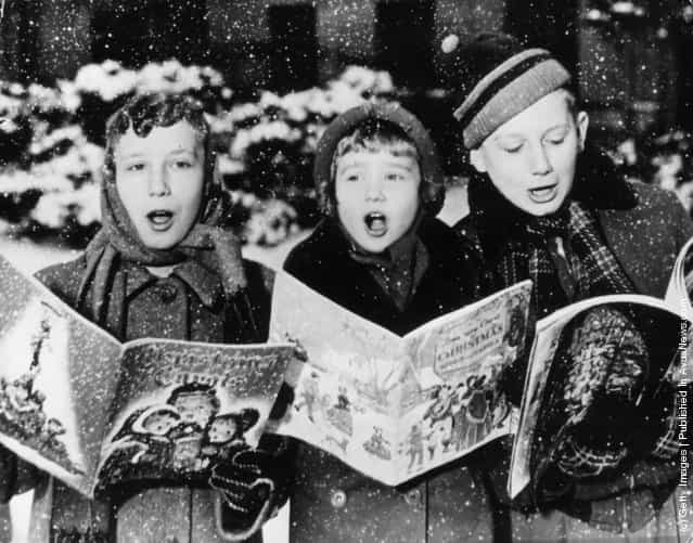 1957: Three young carol singers give their rendering of a Christmas song in the falling snow