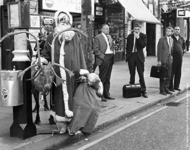 1970: Father Christmas waiting for a bus in the London West End with his reindeer and a sack of presents