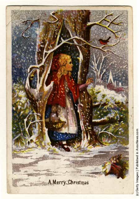 1872: A Christmas greetings card showing a girl in a red cape sheltering from the snow in a hollow tree