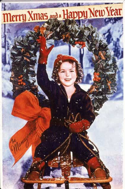 Christmas card or promotional portrait of American child actress Shirley Temple, who rides on a sled and waves, 1930s
