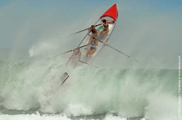 The Piha Womens crew battle a large wave during the Day of Giants Surfboat race regatta at Piha beach