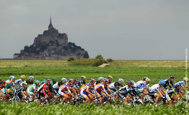 The peloton passes by Le Mont-Saint-Michel at the start of stage six of the 2011 Tour de France from Dinan to Lisieux
