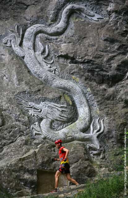 A contestant runs past a dragon engraved on the crag as he competes during the caving session of the Wulong Mountain Quest