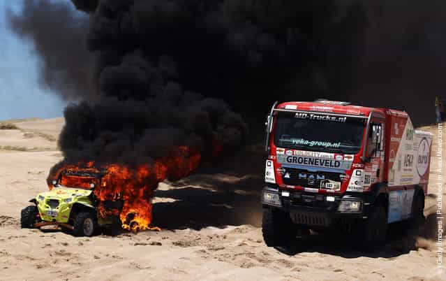 Franz Echter of Germany drives around the burning car of Jose Antonio Blangion of Argentina during stage one of the 2012 Dakar Rally