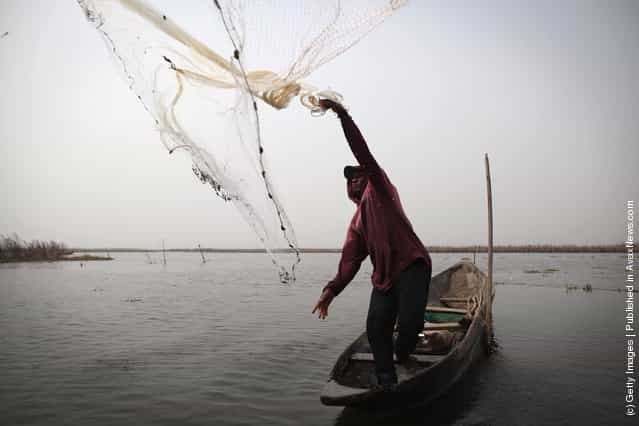 A man casts a net while fishing in the lagoon on his boat near Ganvie, Benin