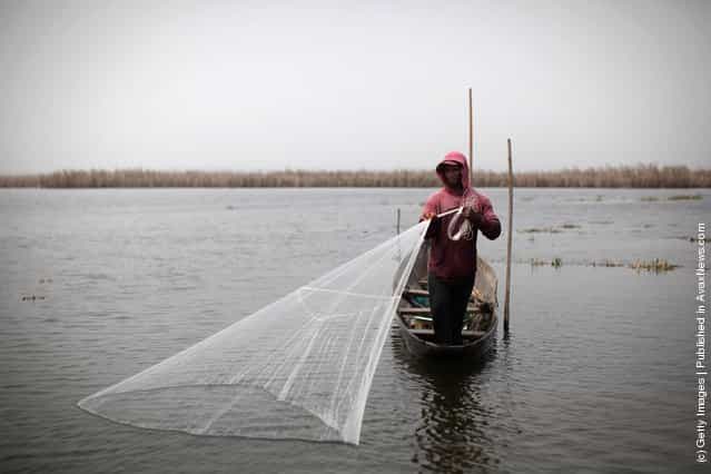 A man casts a net while fishing in the lagoon on his boat near Ganvie, Benin