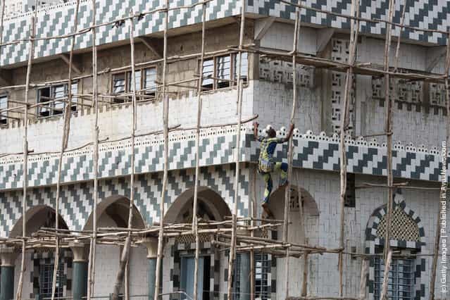 A man climbs the scaffold of a new Mosque, under construction in Ganvie, near Cotonou, Benin