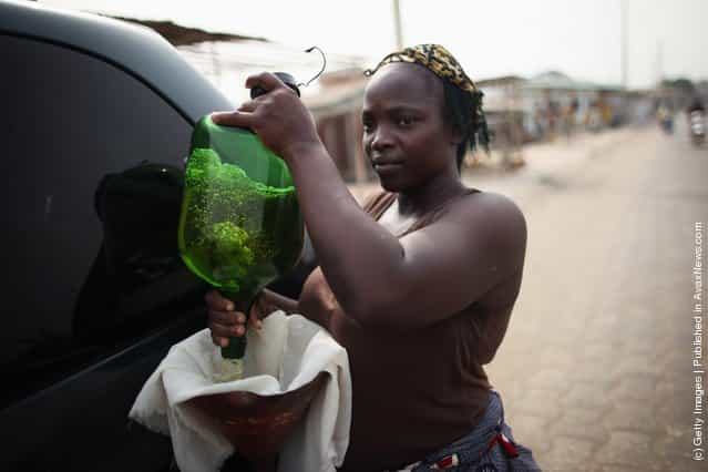 A vendor sells fuel, known locally as 'Kpayo', at the side of the road in Cotonou, Benin