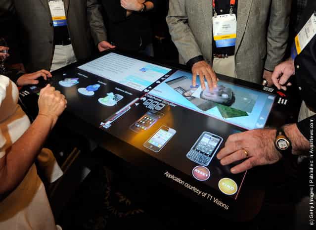Attendees try a prototype 3M Touch Systems 46-inch, projected capacitive display during a press event at The Venetian for the 2012 International Consumer Electronics Show (CES)