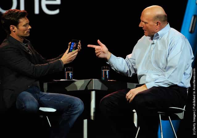 Microsoft CEO Steve Ballmer (L) shows the new Nokia Lumia 900 Windows phone to host Ryan Seacrest as he delivers a keynote address at the 2012 International Consumer Electronics Show