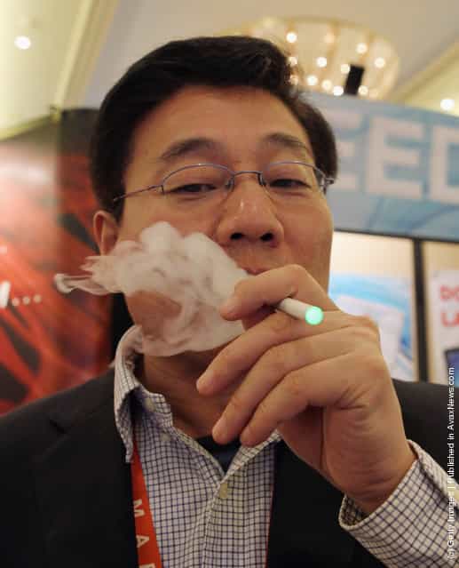 Greg Pan, CEO of Greenworld puffs away on their recently introduced electronic cigarette product which is displayed at the 2012 International Consumer Electronics Show