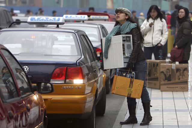 A girl tries to open the door of a taxi as she holds her assembled personal computer in front of an electronics city at Beijings main computer district in Zhongguancun