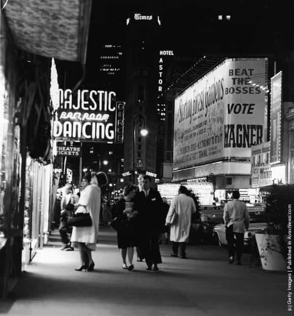 A night street scene at 47th Street near Times Square, showing night club and theater signs, New York City, New York, circa 1958