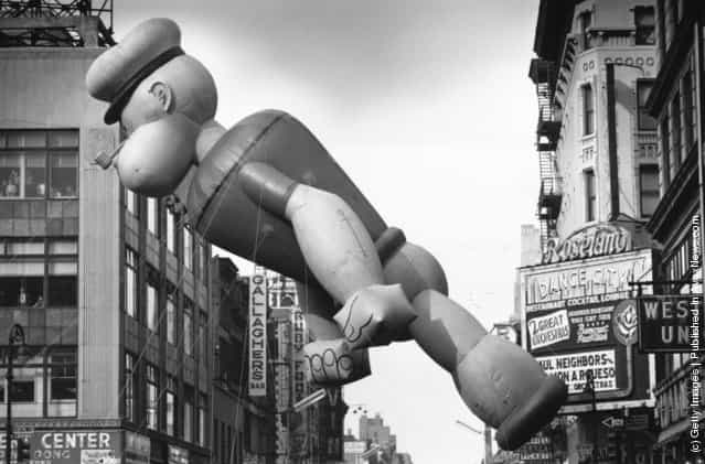 A giant inflatable Popeye floating over Times Square, New York, during a Thanksgiving Parade, 1961