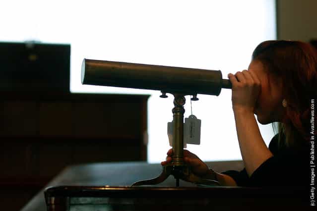 Bonhams employee Victoria Livesey looks at a Gregorian Reflecting Telescope from the early 19th century