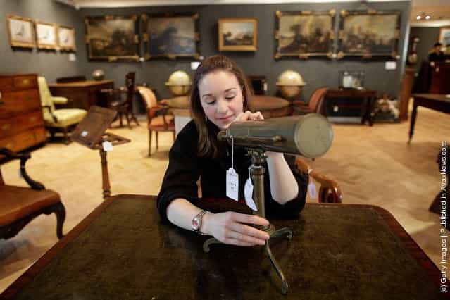 Bonhams employee Victoria Livesey looks at a Gregorian Reflecting Telescope from the early 19th century