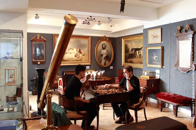 Bonhams employees Tim Lee (L) and and Damien Mabardi (R) play on a Louis XV/XV1 Macassar Ebony and Ivory inlaid Tric Trac table