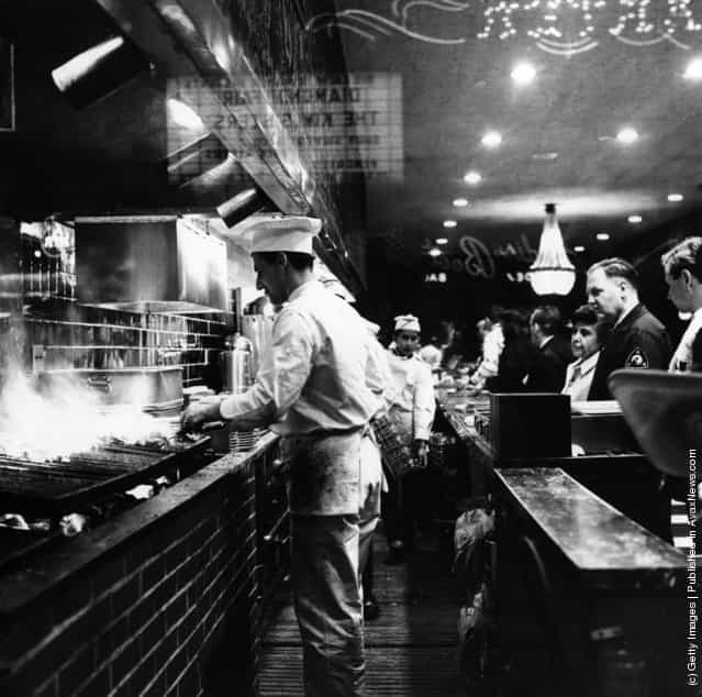 1965: As customers queue up, cooks broil steaks on the charcoal pits at Tads Steak House in Times Square, New York City