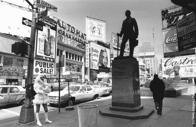 1969: Times Square, New York with the statue of theatrical impresario, George Cohan being studied by a fur coated, mini-skirted passer-by