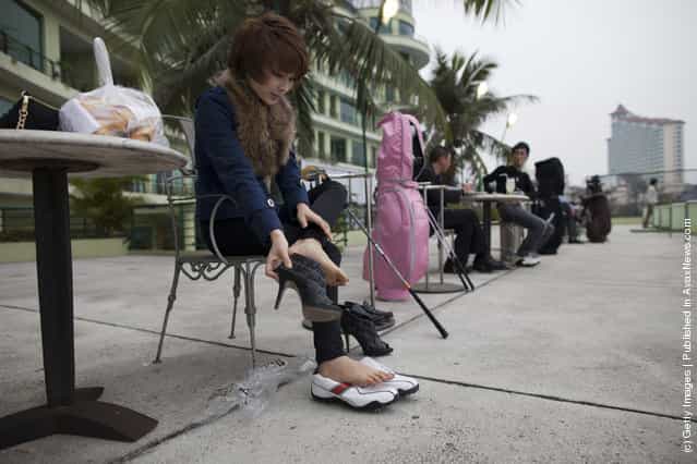 A woman takes her high heels off to get ready to practice driving the balls at the Hanoi club golf center