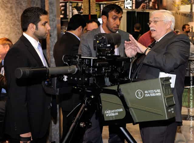 International Golden Group projects manager Saeed Aleghfeli from the United Arab Emirates and Matar Muhair Al Hamiri from the United Arab Emirates Armed Forces look on as Mike Costello with Rheinmetall Electro-Optics shows them a ballistic fire control computer attached to a belt-fed automatic 40mm HK GMG (grenade machine gun) at the Heckler & Koch booth