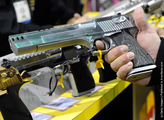 An attendee holds a .50 Action Express (.50 AE) Desert Eagle semi-automatic pistol at the Kahr Arms booth