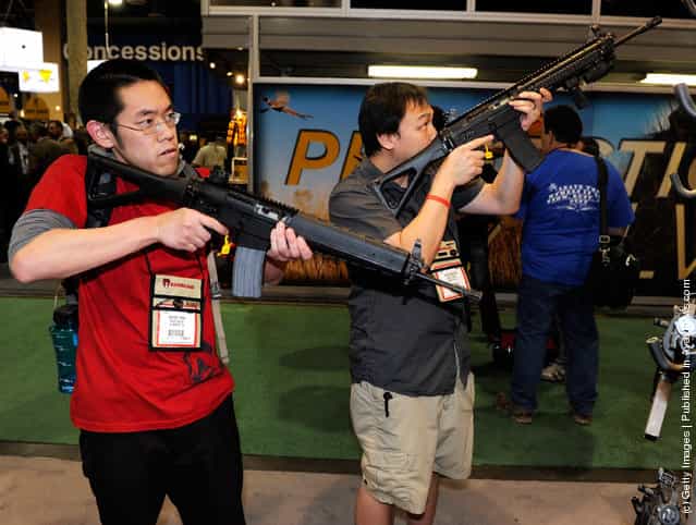 Wayne Tran (L) and Chris Nguyen, both of California, look at SIG556 semi-automatic rifles at the Sig Sauer booth