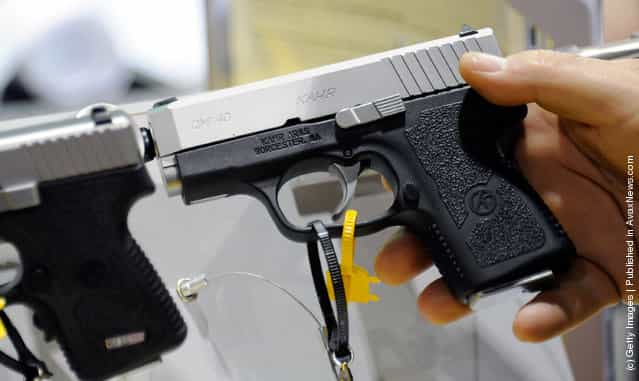 An attendee holds a Kahr Arms CM40 pistol at the company's booth