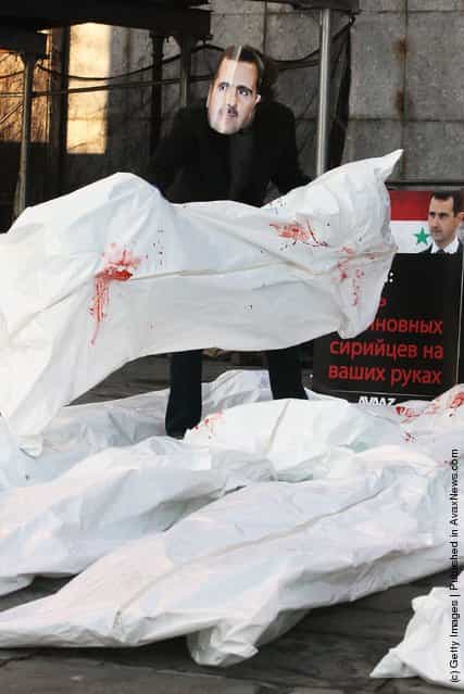 Actors wearing masks of Syrian President Bashar al-Assad and Russian Prime Minister Vladimir Putin perform with body bags during a demonstration outside United Nations headquarters