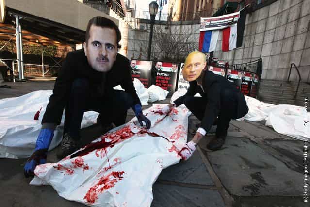 Actors wearing masks of Syrian President Bashar al-Assad and Russian Prime Minister Vladimir Putin perform with body bags during a demonstration outside United Nations headquarters